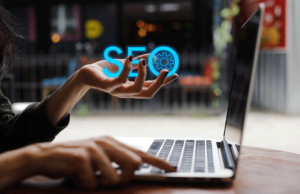 Woman on laptop with the text "SEO" in her hand