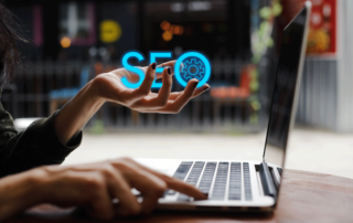 Woman on laptop with the text "SEO" in her hand